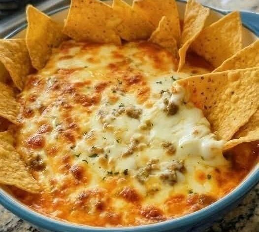 Texas Trash Dip baked with melted cheese and tortilla chips in a serving dish